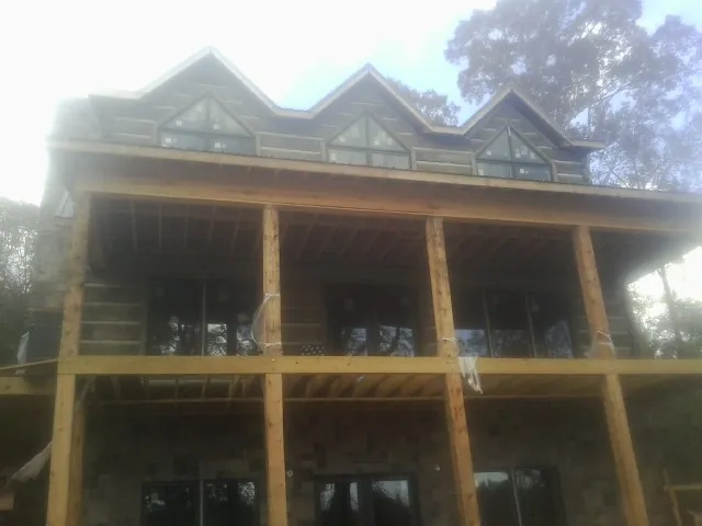 Dormers and porch framing on a large log home under construction — Roof Coating work by our crew in Herington
