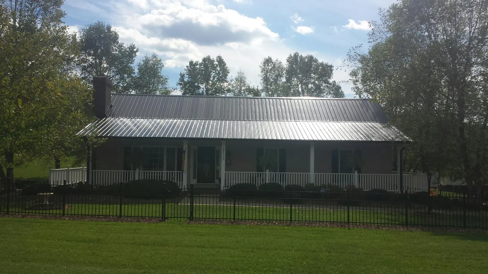 Gray metal roof on a brick ranch with a full width front porch — Gutter Guard Installation work by our crew in Herington