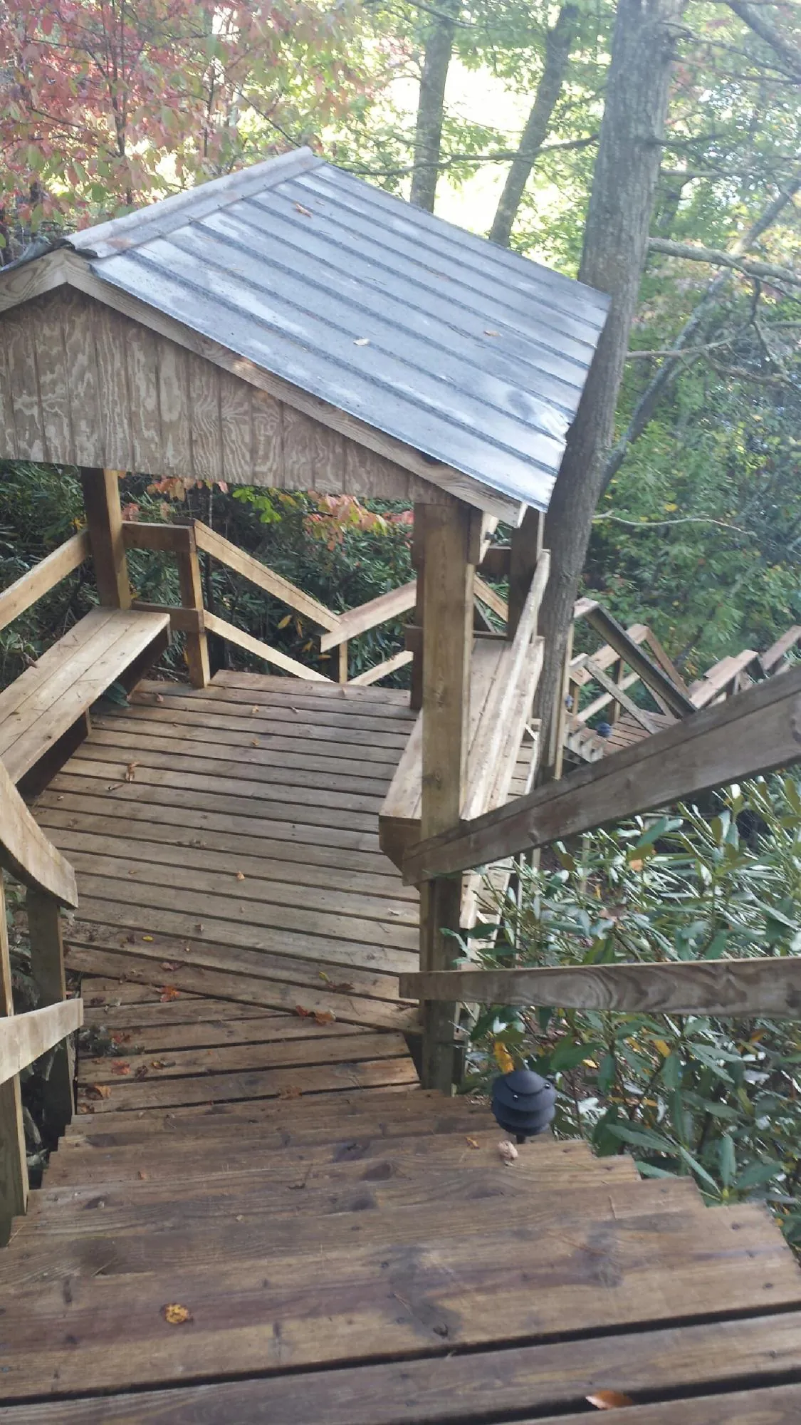 Metal roofed shelter over wooden steps on a wooded walkway — Skylight Repair & Installation work by our crew in Herington