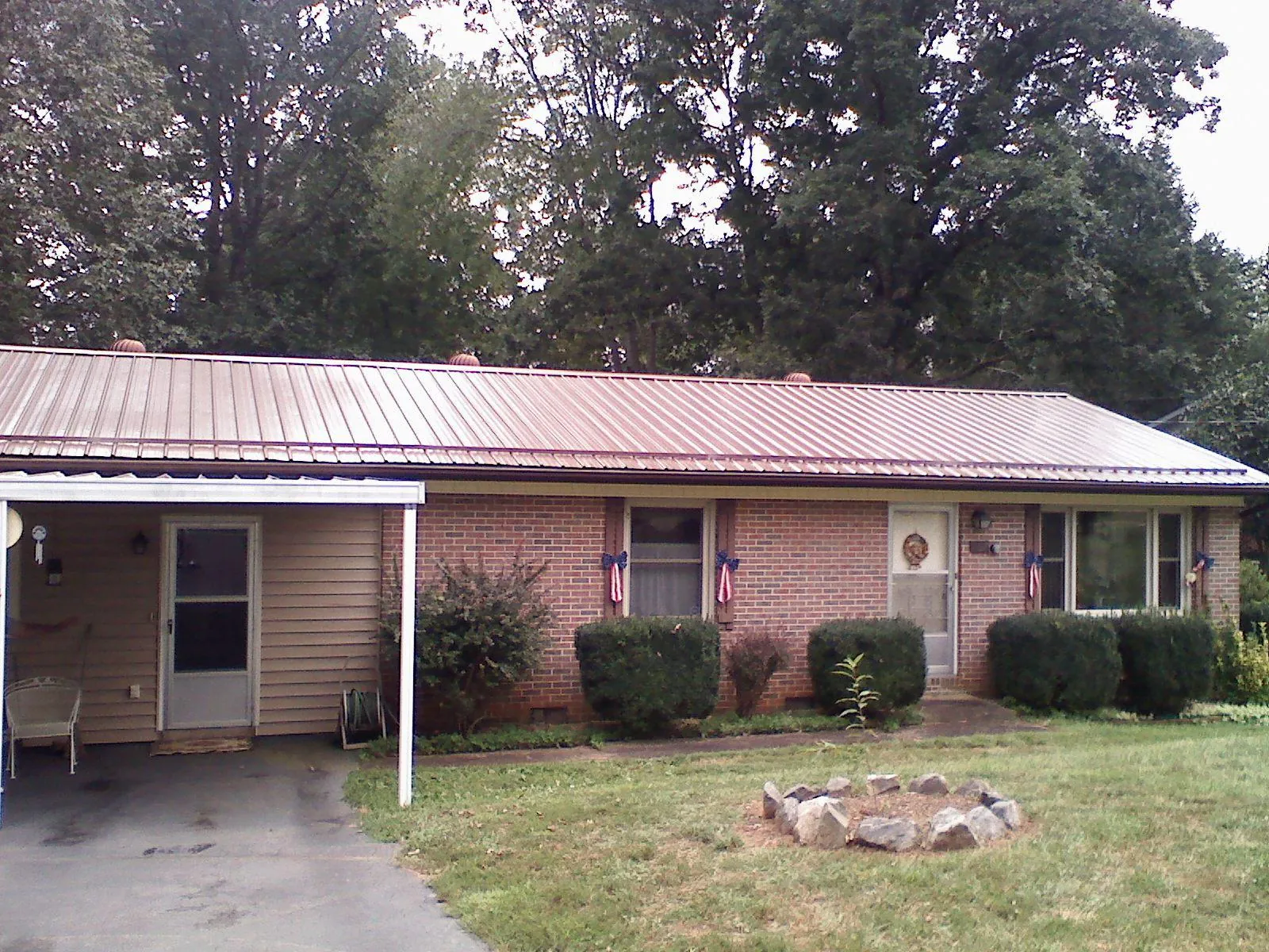 Bronze metal roof and carport on a brick ranch home — Roof Repair work by our crew in Herington